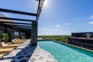 a swimming pool on the roof of a building with chairs at Designer Cave Condo with Beach Club included - Hotel Zone Tulum in Tulum