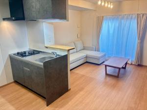 eine Küche mit einem Waschbecken und einem Sofa in einem Zimmer in der Unterkunft In time tokyo in Ichikawa