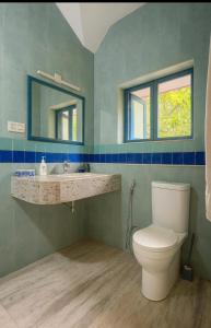 a bathroom with a toilet and a sink and two windows at NeelaHouse in Kovalam