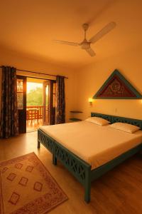 a bedroom with a large bed with a ceiling fan at NeelaHouse in Kovalam