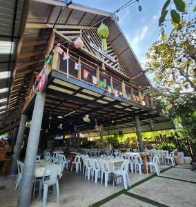 a restaurant with white tables and white chairs at Maderlar Farm Restaurant & Resort in Ban Kao Lieo
