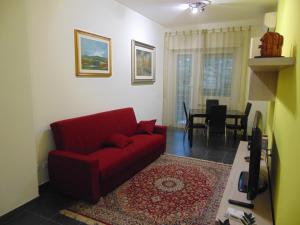 Studiohouserome في روما: غرفة معيشة مع أريكة حمراء وغرفة طعام