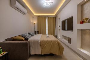 a bedroom with a bed and a couch and a tv at Elmswater court in St. Paul's Bay