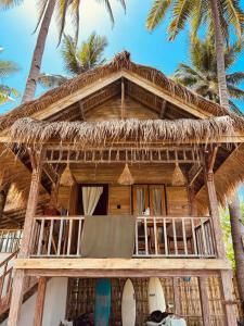 a straw hut with a balcony and palm trees at Living On Air in Pulau Sarang +45 photos