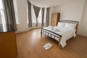 een slaapkamer met een bed en twee slippers op de vloer bij Big Double room wimbledon Park in Londen