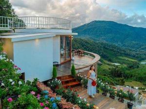 a woman standing on a balcony of a house at Rai hemuxnfa Villa in Mae Rim