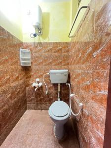 een badkamer met een toilet en een lampje aan de muur bij Maison De Ravi in Pondicherry