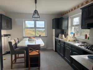 a kitchen with black cabinets and a table with chairs at 3 bed house with stunning views on Achill Island in Sraheens