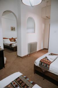 een kamer met 2 bedden en 2 ramen bij Victoria Hotel in Jeruzalem