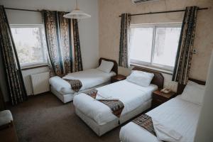 een kamer met 3 bedden en 2 ramen bij Victoria Hotel in Jeruzalem