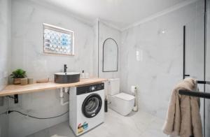 Boutique home in the heart of Surfers Paradise في غولد كوست: حمام مع مغسلة وغسالة ملابس