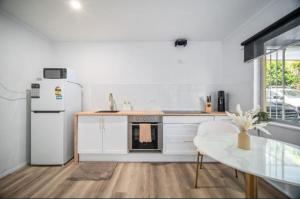 Boutique home in the heart of Surfers Paradise في غولد كوست: مطبخ مع ثلاجة بيضاء وطاولة