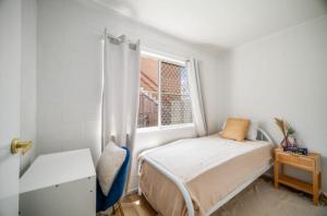 Boutique home in the heart of Surfers Paradise في غولد كوست: غرفة نوم صغيرة بها سرير ونافذة +صورة واحدة