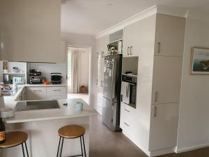 a white kitchen with a counter and stools in it at Lonny Coastal Escape in Point Lonsdale