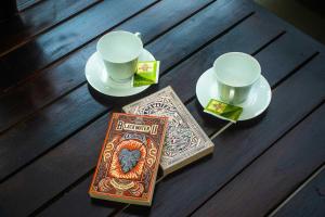 a table with a book and a cup and saucers and a coffee mug at Orange Jesmine Unawatuna in Unawatuna