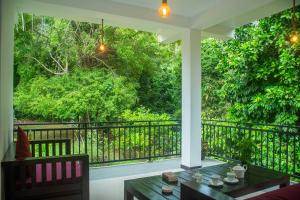 a balcony with a table and a view of a forest at Orange Jesmine Unawatuna in Unawatuna