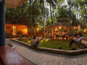 a group of people sitting in a garden at night at NeelaHouse in Kovalam