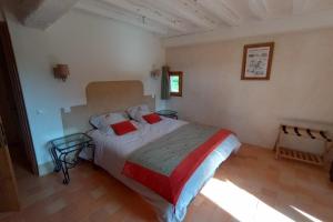 Un dormitorio con una cama con dos almohadas rojas. en La Grande Métairie Notz Marafin, en Paulnay