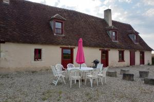 Una mesa con sillas y una sombrilla rosa frente a una casa. en La Grande Métairie Notz Marafin, en Paulnay 50 fotos más