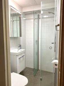 a bathroom with a glass shower and a sink at Studio Tokoi in Helsinki
