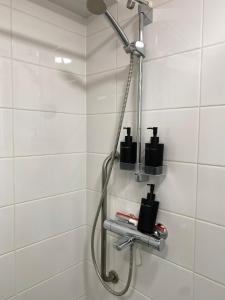 a shower in a white tiled bathroom at Studio Tokoi in Helsinki
