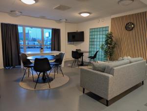 een woonkamer met een bank, een tafel en stoelen bij Kotimaailma - Vihtyisä Hostelli in Kokkola