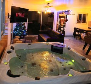 een hot tub in een woonkamer met een kerstboom bij Logement insolite avec Jeux et Jacuzzi in Soulosse-sous-Saint-Élophe