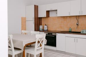a kitchen with white cabinets and a table and chairs at Large and charming apartment near beach with big & sunny terrace in Sumartin