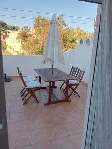 een tafel met een parasol en 2 stoelen op een balkon bij ÁTICO RESIDENCIAL MARIANA parking privado y piscina in Rincón de la Victoria
