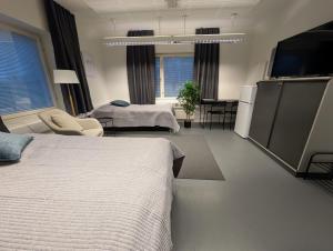 een slaapkamer met twee bedden en een flatscreen-tv bij Kotimaailma - Vihtyisä Hostelli in Kokkola