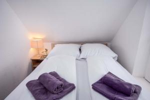a white bed with two purple towels on it at Ferienwohnung Krabbe in Manslagt