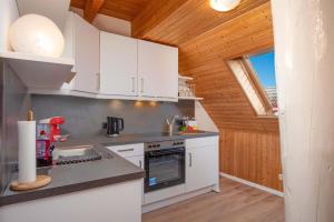 a kitchen with white appliances and a wooden ceiling at Ferienwohnung Hummer in Manslagt