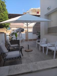 an umbrella sitting on a patio with chairs and tables at Villetta Angela in Torre San Giovanni Ugento