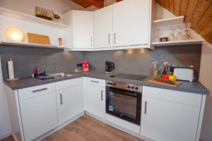 a kitchen with white cabinets and a sink at Ferienwohnung Hummer in Manslagt +19 photos