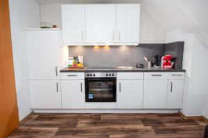 a kitchen with white cabinets and a sink at Ferienwohnung Auster in Manslagt