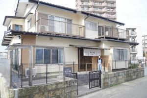 eine Person, die vor einem Gebäude steht in der Unterkunft 宇都宮ゲストハウス花ニ嵐 in Utsunomiya