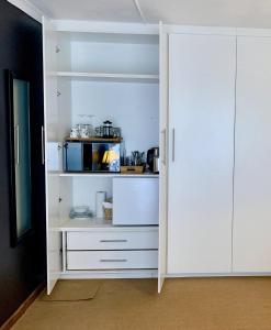 a kitchen with white cabinets and a pantry at Ikhaya le Inkhuku A cozy retreat in Sunrise-on-Sea in Sunrise-on-Sea
