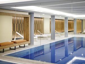 a swimming pool with chairs and tables in a building at Novotel München City in Munich