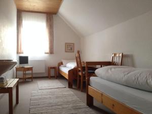 a bedroom with two beds and a table and a desk at PensionSchilling in Grasbrunn