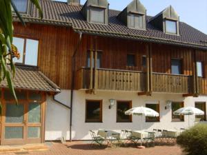 a building with tables and umbrellas in front of it at PensionSchilling in Grasbrunn