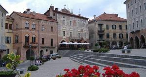 a group of buildings with red flowers in a courtyard at Dimora Vico in Mondovì