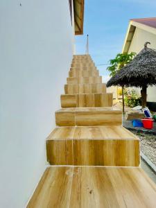 a wooden staircase leading up to a house with a straw umbrella at Leo Home in Nungwi