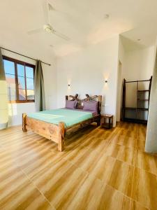 a bedroom with a bed in a room with wooden floors at Leo Home in Nungwi