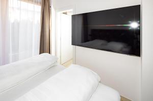 a bedroom with a white bed and a flat screen tv at ZUEGG Suiten in Lienz