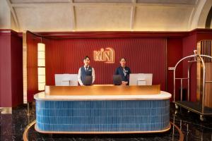 two men standing at a reception desk in a room at KiN Hotel Onsen in Ho Chi Minh City