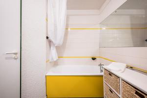 La salle de bains est pourvue d'une baignoire jaune et blanche. dans l'établissement Appartement Necou 105, aux Menuires