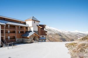 un bâtiment situé sur le côté d'une montagne enneigée dans l'établissement Appartement Necou 105, aux Menuires