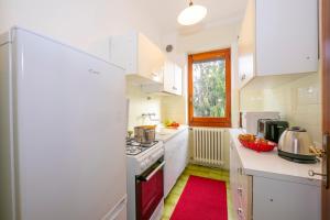 a kitchen with white cabinets and a red rug at Villa La Verbanina Private Garden - Happy Rentals in Ghiffa