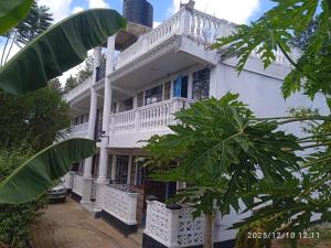 Casa blanca con balcón y palmeras en Polycap Cottage Home, en Murangʼa