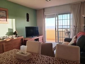 een woonkamer met een televisie en een tafel met stoelen bij Superb Location! in Plettenbergbaai +3 foto's